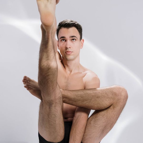 A man holding a challenging balance pose, showing concentration and body control.